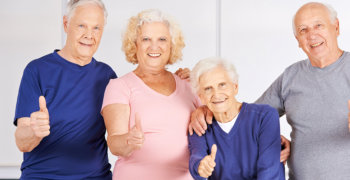 Happy group of seniors holding thumbs up in a nursing home